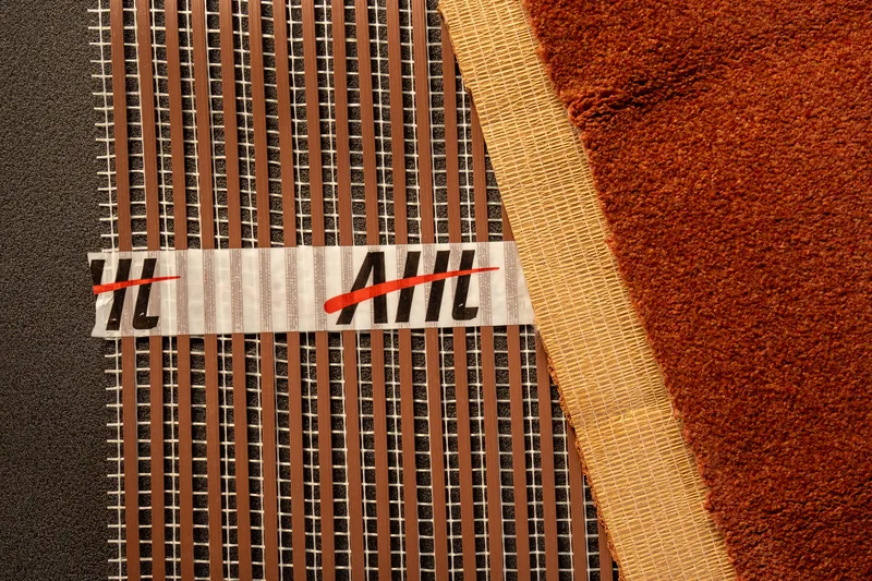 Carpet and backing sample beside a ribbon underfloor heating mat.