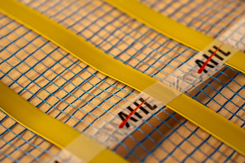 Close-up of parallel heating strips on blue mesh.