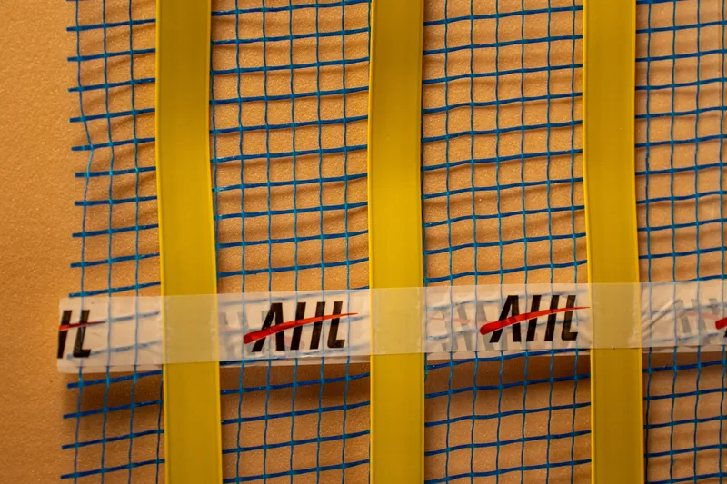 Parallel heating strips and branded tape on a blue-mesh sample.